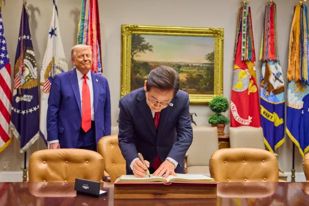 الرئيس الكوري الجنوبي لي جاي ميونغ يوقع في سجل الزوار بينما يراقبه دونالد ترمب في البيت الأبيض (إ.ب.أ)