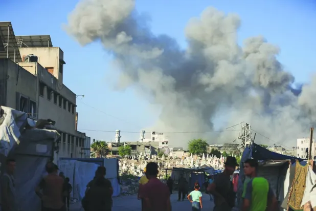 Filistinliler, dün Gazze Şehri'nde İsrail'in düzenlediği saldırıda meydana gelen patlamanın ardından yükselen dumanı izliyor (Reuters)