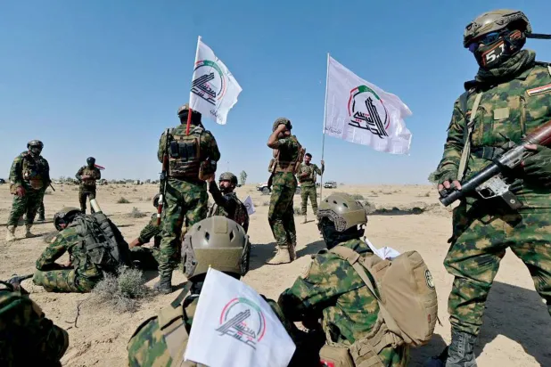  مقاتلون يرفعون شعار «الحشد الشعبي» خلال تدريبات عسكرية (موقع الهيئة)