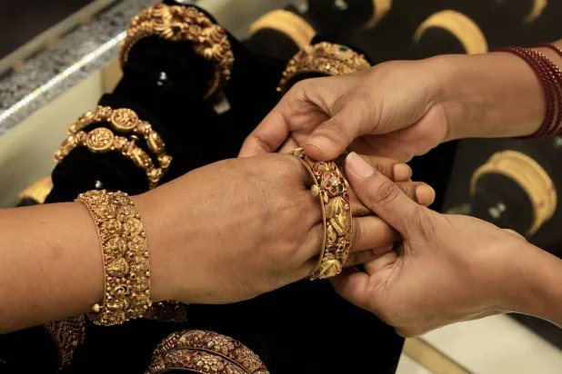 امرأة هندية تُجرّب حُلياً ذهبية في متجر مجوهرات في بنغالور بالهند (إ.ب.أ)