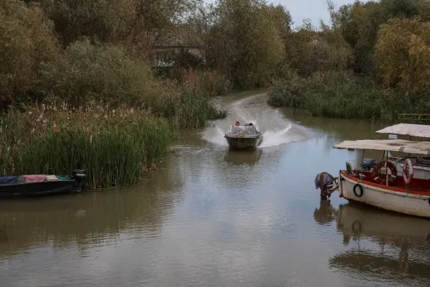 سكان يبحرون عبر قناة في قارب في بلدة فيلكوفي بمنطقة أوديسا الأوكرانية (رويترز - أرشيفية)