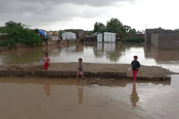 أطفال يمنيون يلعبون وسط تجمع لمياه الأمطار جنوب محافظة الحديدة (أ.ف.ب)