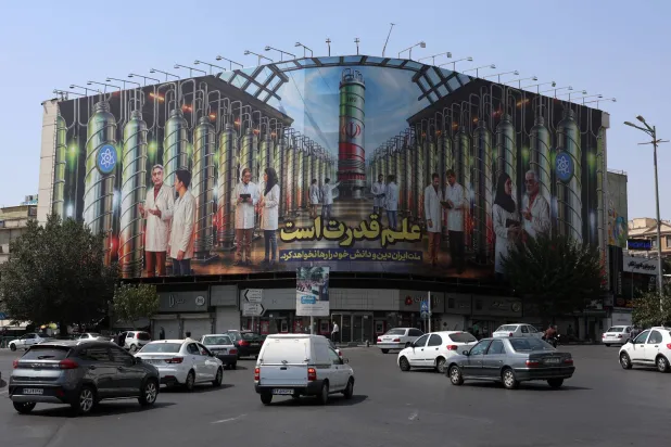 ميدان انقلاب في طهران وتظهر في الصورة المأخوذة الجمعة لوحة إعلانية تبين أجهزة طرد مركزي نووية وجملة باللغة الفارسية تقول «العلم هو القوة» (إ.ب.أ)