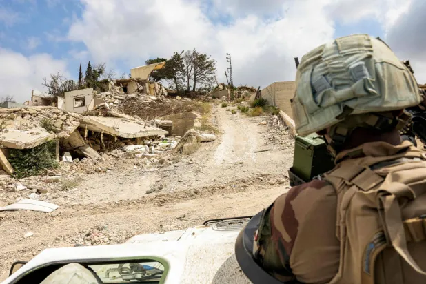 جندي في «اليونيفيل» على متن آلية عسكرية تعبر بين المنازل المدمرة في بلدة كفر كلا بجنوب لبنان (أ.ف.ب)