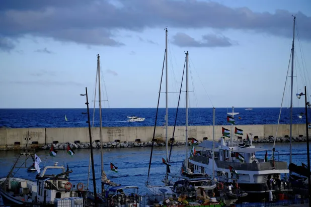 أعلام فلسطين ترتفع على قوارب «أسطول الصمود العالمي» التي من المقرر أن تبحر من برشلونة في اتجاه غزة (رويترز) 
