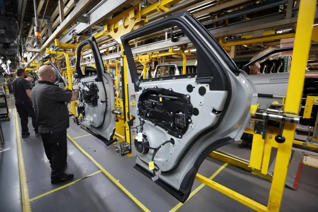 موظفون يجمعون لوحات الأبواب على خط الإنتاج بمصنع «جاغوار لاند روفر» في هالوود (رويترز)