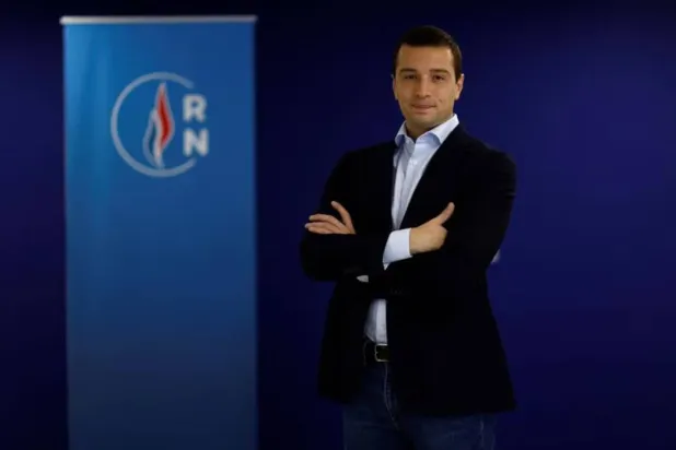 رئيس حزب «التجمّع الوطني» جوردان بارديلا في صورة كان حينها مرشحاً لرئاسة الحزب، وإلى جانبه شعار الحزب، 26 أكتوبر 2022 (رويترز)