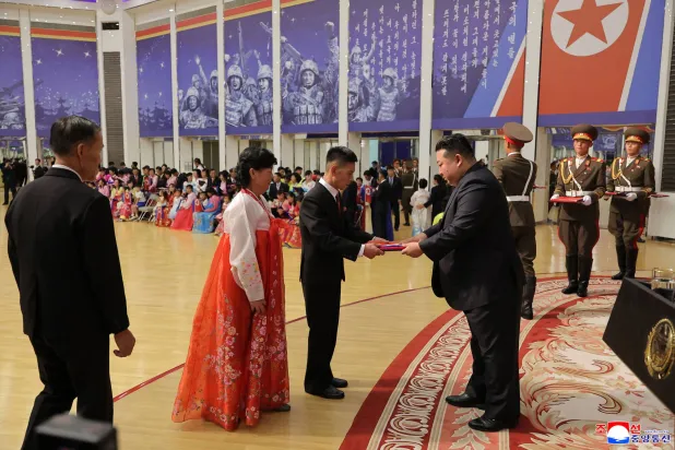  كيم يسلم صورة ملفوفة بالعلم الكوري الشمالي لعائلة جندي شارك في العمليات العسكرية الخارجية في بيونغ يانغ (أ.ف.ب)