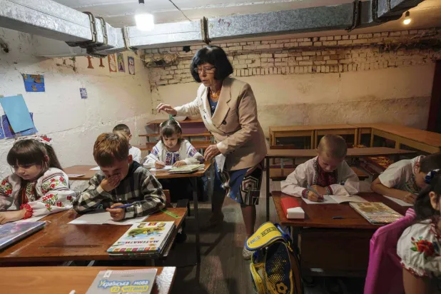 طلاب ومعلّمتهم خلال حصة تعليمية في طابق تحت الأرض بمبنى البلدية خلال اليوم الأول في المدرسة في بوبريك بمنطقة سومي في أوكرانيا - 1 سبتمبر 2025 (أ.ب)