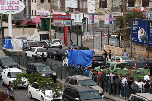 جنود ومواطنون يقفون بجوار شاحنة تحمل أسلحة خلال عملية تسليمها من مخيم برج البراجنة جنوب بيروت (إ.ب.أ)