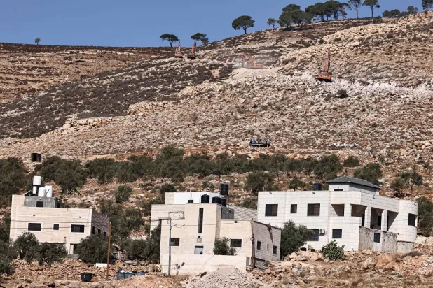 Israeli settlers use bulldozers to pave a road for a new settlement on the outskirts of the occupied West Bank village of Al-Mughayyir, north of Ramallah, on August 24, 2025. (Photo by Zain JAAFAR / AFP)