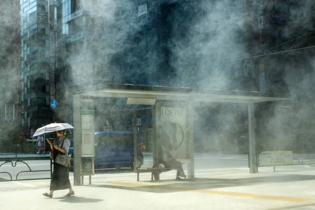 امرأة تحمل مظلة وتسير تحت أشعة الشمس الحارقة في طوكيو (أ.ف.ب)