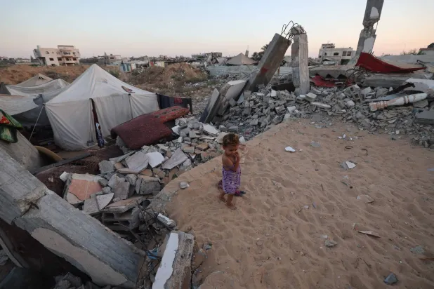 طفلة فلسطينية بجانب أطلال مبنى مدمر في مخيم البريج للنازحين بوسط قطاع غزة (أ.ف.ب) 