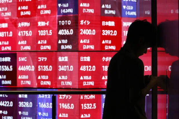 رجل يمر أمام شاشة تعرض حركة الأسهم داخل مقر البورصة في العاصمة اليابانية طوكيو (إ.ب.أ)