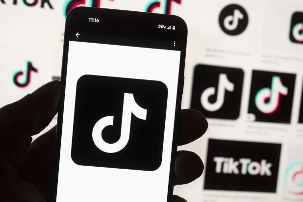 The TikTok logo is seen on a mobile phone in front of a computer screen which displays the TikTok home screen, Oct. 14, 2022, in Boston. (AP)