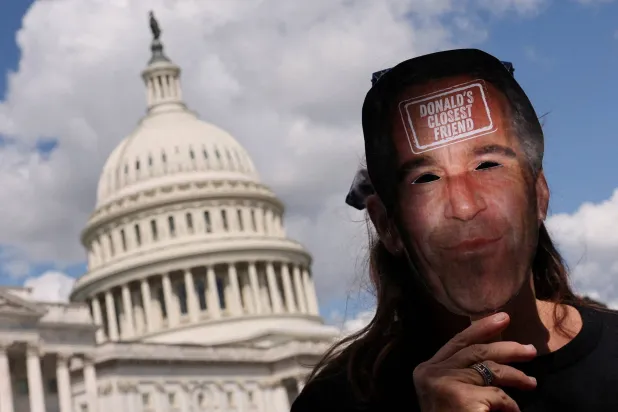 متظاهر مناهض لترمب يحمل قناعاً يصور جيفري إبستين يسير في مبنى الكابيتول الأميركي بواشنطن (رويترز)