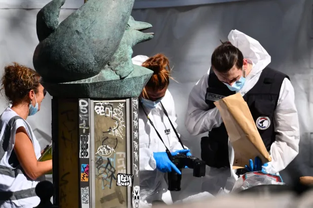 عناصر الشرطة العلمية خلال عملية تجميع الأدلة من مكان الحادث (أ.ف.ب)