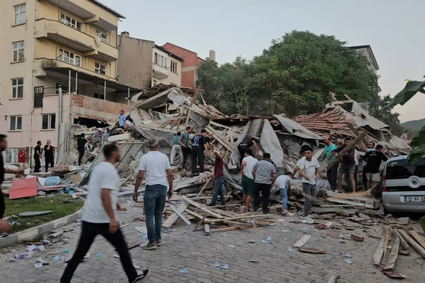 أشخاص يبحثون عن ناجين تحت أنقاض مبنى منهار بعد زلزال ضرب سينديرجي في مقاطعة باليكسير شمال غربي تركيا الشهر الماضي (رويترز)