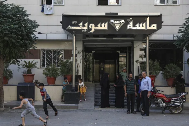 نازحون من بدو السويداء أمام مدخل فندق جرى تحويله إلى مركز إيواء في بلدة السيدة زينب قرب دمشق (أ.ب)