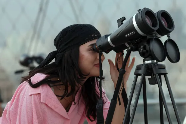 إيرانية تشاهد الخسوف الكلي للقمر من خلال تلسكوب على جسر في طهران (إ.ب.أ)