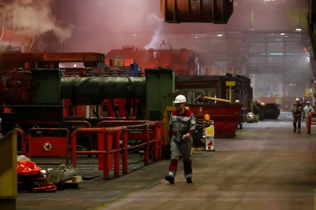 عمال في شركة «تيسنكروب» يسيرون في مصنع الصلب التابع للشركة في دوسلدورف (رويترز)