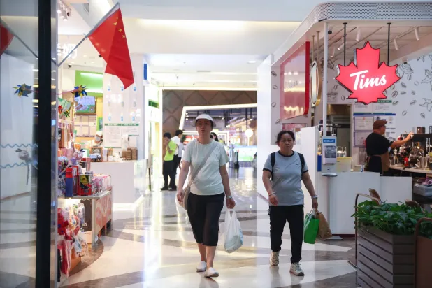 سيدتان في أحد المراكز التجارية بالعاصمة الصينية بكين (إ.ب.أ)