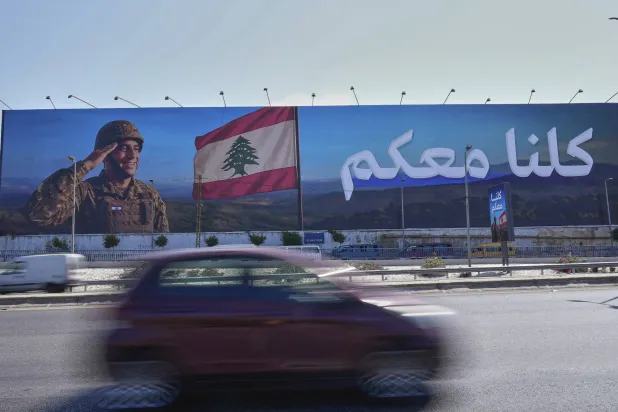 سيارة تمر أمام لوحة إعلانية لدعم الجيش اللبناني موضوعة على الطريق السريع المؤدي إلى مطار بيروت الدولي (أ.ب)