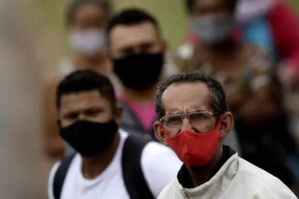 أشخاص يرتدون أقنعة الوجه الواقية خلال انتظارهم ركوب إحدى الحافلات في البرازيل (أرشيفية- أ.ب)