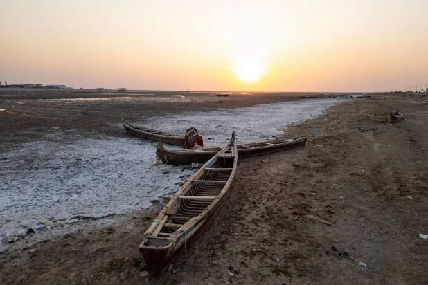 قوارب صيد خشبية تقليدية مهجورة في أهوار جافة بمحافظة البصرة جنوب العراق (أ.ف.ب)