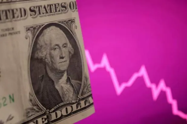 ورقة نقدية بالدولار الأميركي إلى جانب مخطط للأسهم يظهر انخفاضها (رويترز)