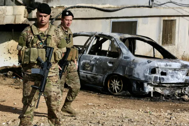 عنصران من الجيش اللبناني في محيط سيارة استهدفتها غارة إسرائيلية بجبل لبنان الثلاثاء (إ.ب.أ)