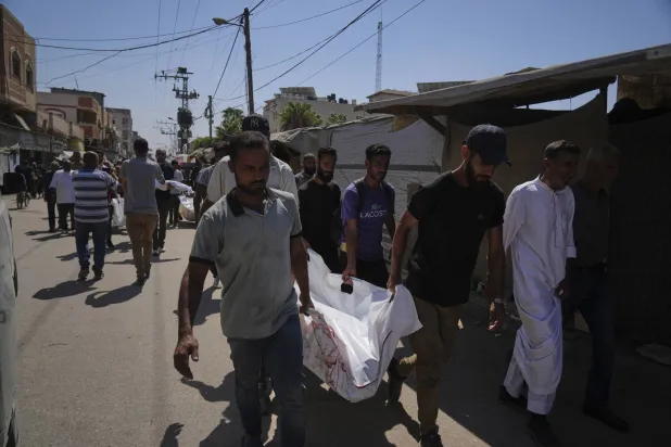 فلسطينيون يحملون جثمان سيدة فلسطينية تُدعى علياء أبو عودة قُتلت أمس في غارات إسرائيلية على دير البلح (أ.ب)