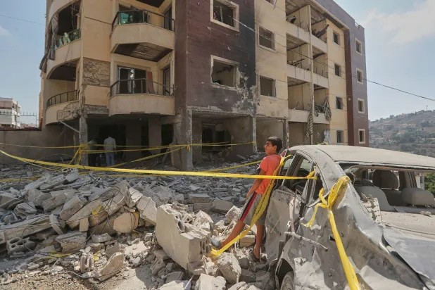 طفل يقف إلى جانب المبنى الذي استهدف في النبطية مساء الاثنين (أ.ب)