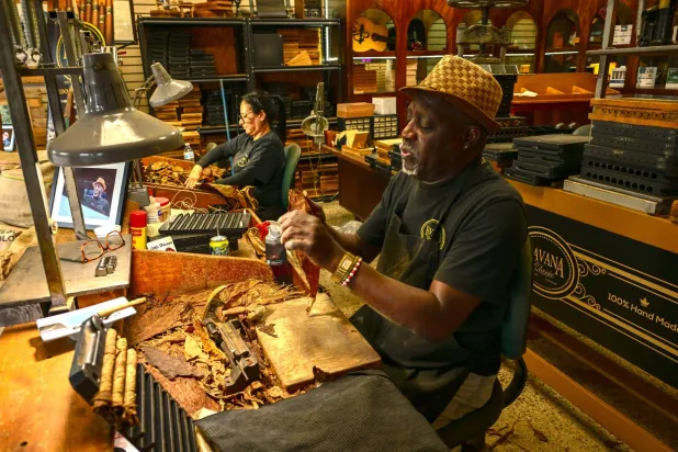 عمال متجر تبغ يلفّون السيجار في حي ليتل هافانا (أ.ف.ب)