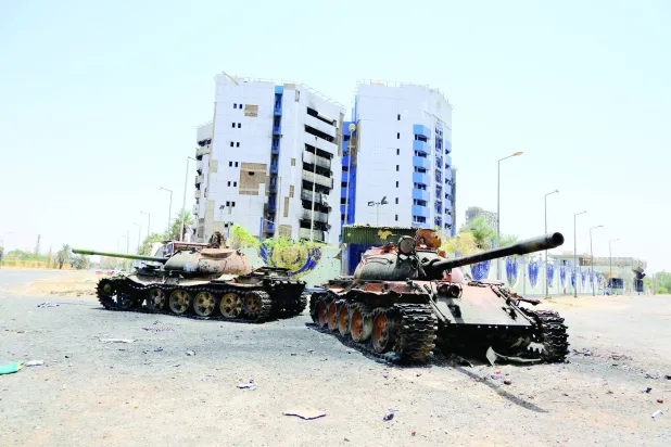 دبابتان متضررتان أمام مبنى «البنك المركزي» السوداني في الخرطوم (رويترز)