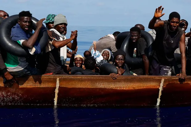 امرأة تحمل طفلها في أثناء إبحارهما على متن قارب حديدي في المياه الدولية جنوب لامبيدوزا وسط البحر المتوسط (رويترز - أرشيفية)