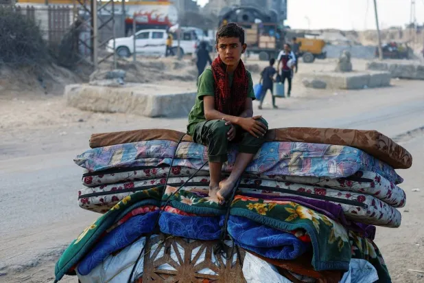 A displaced Palestinian boy, fleeing northern Gaza due to an Israeli military operation, sits atop belongings as he moves southward after Israeli forces ordered residents of Gaza City to evacuate to the south, in the central Gaza Strip September 17, 2025. (Reuters)