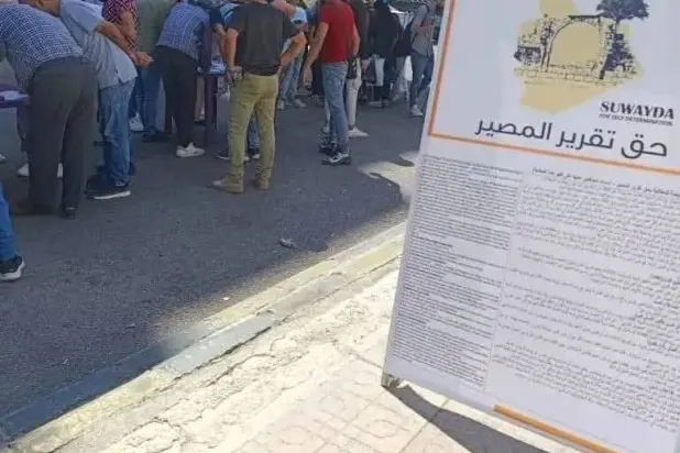 لافتة كبيرة في مدينة السويداء جنوب سوريا تدعو للتوقيع على حملة حق تقرير المصير (أخبار السويداء)