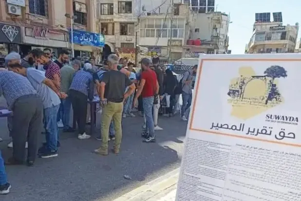 لافتة كبيرة في مدينة السويداء جنوب سوريا تدعو للتوقيع على حملة حق تقرير المصير (أخبار السويداء)