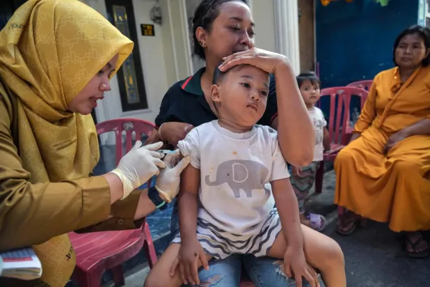 Endonezya'nın Surabaya kentinde bir çocuğa kızamık aşısı yapan bir sağlık çalışanı (AFP)