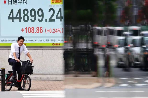 رجل بدراجة يمر أمام لوحة إلكترونية تعرض حركة الأسهم وسط العاصمة اليابانية طوكيو (رويترز)