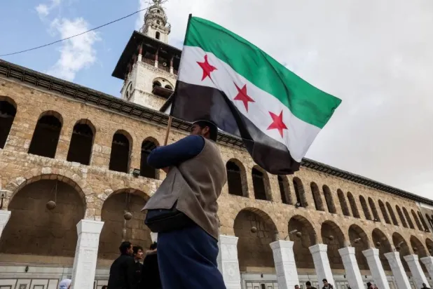 رجل يحمل العلم السوري في الجامع الأموي بدمشق (رويترز)