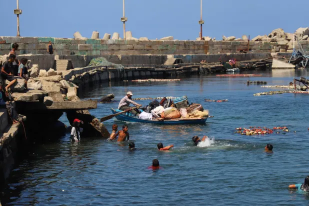فلسطينيّ يحاول النزوح بأمتعته في قارب فراراً من مدينة غزة يوم الخميس (رويترز)