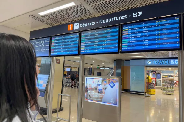 سيدة تقف أمام جدول وصول الرحلات الجوي في مطار باريس - أورلي جنوب فرنسا (أ.ف.ب)