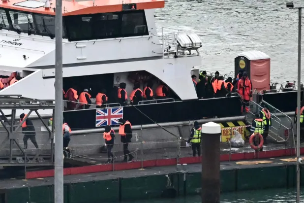 مهاجرون تم إنقاذهم في البحر أثناء محاولتهم عبور القنال الإنجليزية من فرنسا ينزلون من سفينة «تايفون» التابعة لقوة الحدود بعد وصولها إلى مارينا دوفر بجنوب شرقي إنجلترا يوم 13 يناير 2025 (أ.ف.ب)
