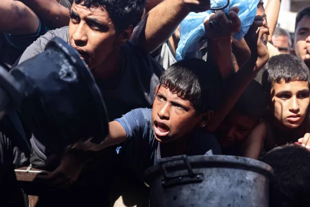 نازحون فلسطينيون يشقون طريقهم بصعوبة أمام مطبخ جماعي في خان يونس جنوب قطاع غزة أمس (أ.ف.ب)