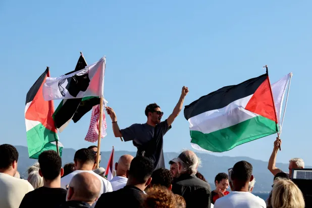 ناشطون يلوحون بالأعلام الفلسطينية في جزيرة كورسيكا الفرنسية المطلة على البحر الأبيض المتوسط (أ.ف.ب)