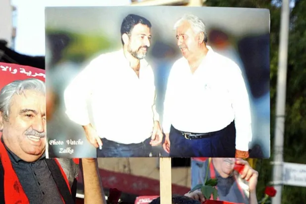 Elias Atallah (not seen) holds a photo of George Hawi and Samir Kassir during Kassir’s funeral in 2005 (AFP)