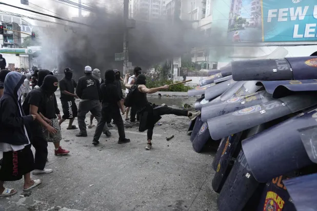 يحاول المتظاهرون كسر صفوف الشرطة خلال مناوشات أثناء محاولتهم دخول مجمع القصر الرئاسي مالاكانانج في مانيلا (أ.ب)