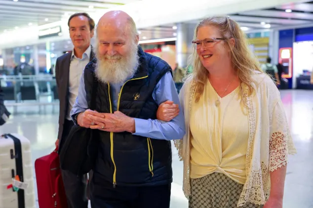 بيتر رينولدز يمشي مع ابنته سارة إنتويستل، بينما يصل هو وزوجته باربي رينولدز (غير مصورة) إلى مبنى الركاب رقم 4 بمطار هيثرو بعد إطلاق سراحهما من احتجاز طالبان في أفغانستان، في لندن الكبرى، بريطانيا، 20 سبتمبر أيلول 2025  (رويترز)